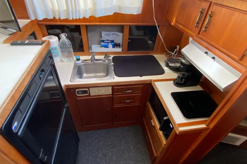 Slide: The Image of 1986 Tollycraft Flybridge Convertible kitchen with sink, stove, and wooden cabinetry. - 9