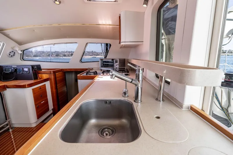 Slide: The Image of Interior of 2012 Outremer 49 yacht featuring modern kitchen with sink and wooden cabinetry. - 16