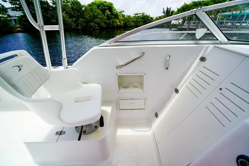 Slide: The Image of 1999 Pro-Line 201 Walkaround boat interior with seating and storage, near a scenic waterway. - 13