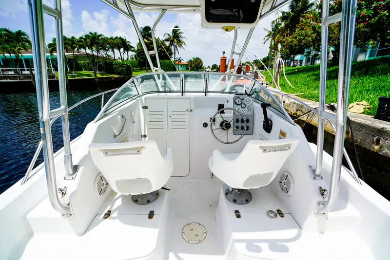 Slide: The Image of 1999 Pro-Line 201 Walkaround boat interior with dual seats and control panel, docked by a canal. - 8