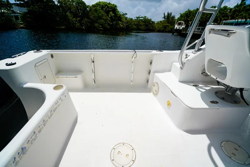 Slide: The Image of 1999 Pro-Line 201 Walkaround boat interior, featuring spacious deck and seating near a serene waterway. - 9