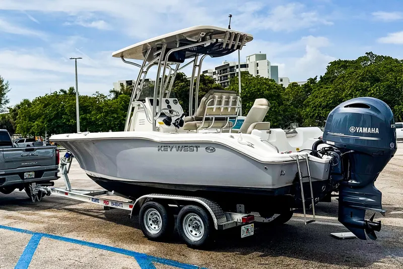 The Image of 2022 Key West 219 FS boat on trailer with Yamaha engine in parking lot. - 0