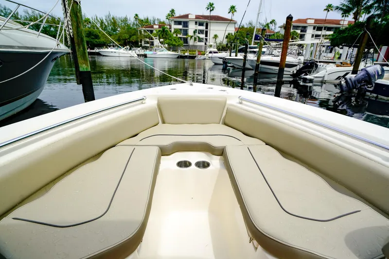 Slide: The Image of 2022 Key West 219 FS boat interior at marina, featuring beige seating and cup holders. - 19