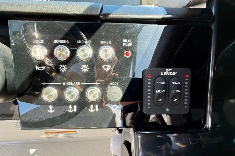 Slide: The Image of Control panel of 2025 Sea Ray SLX 280 Outboard with various switches and Lenco trim tabs. - 36