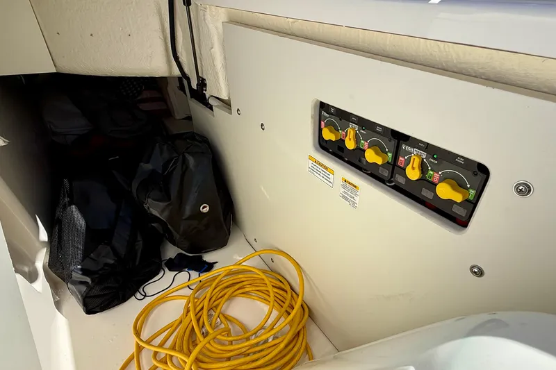 Slide: The Image of 2025 Sea Ray SLX 280 Outboard storage area with control panel and coiled yellow cable. - 52