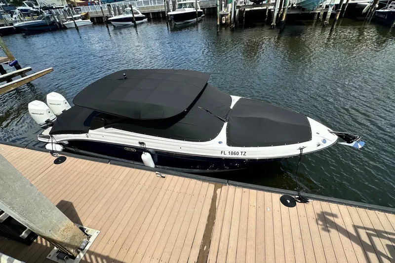 Slide: The Image of 2025 Sea Ray SLX 280 Outboard boat docked, covered with black canvas, in a marina. - 56