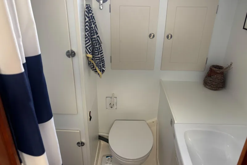 Slide: The Image of Hallberg-Rassy 46 yacht bathroom, featuring toilet, sink, and storage cabinets, 2000 model. - 21