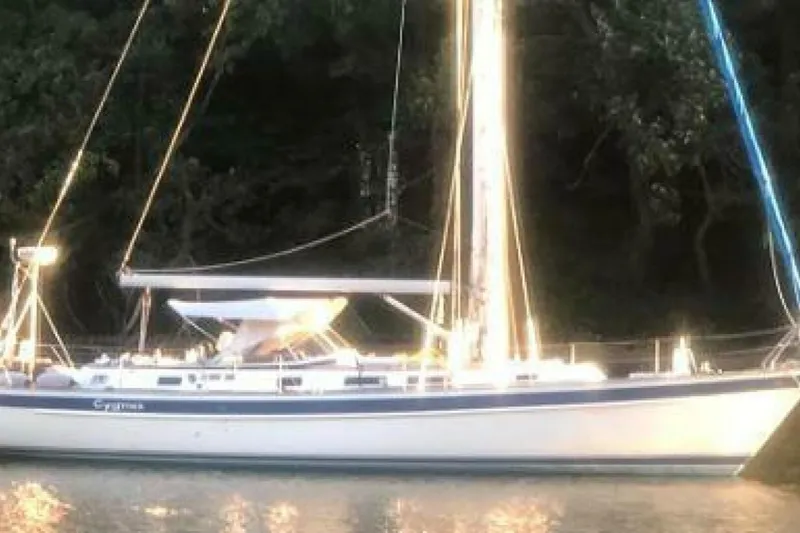 Slide: The Image of Hallberg-Rassy 46 sailboat from 2000, anchored near a forested shoreline. - 26