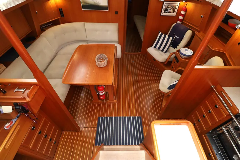 Slide: The Image of Interior of 2000 Hallberg-Rassy 46 yacht with wooden flooring and cozy seating area. - 4
