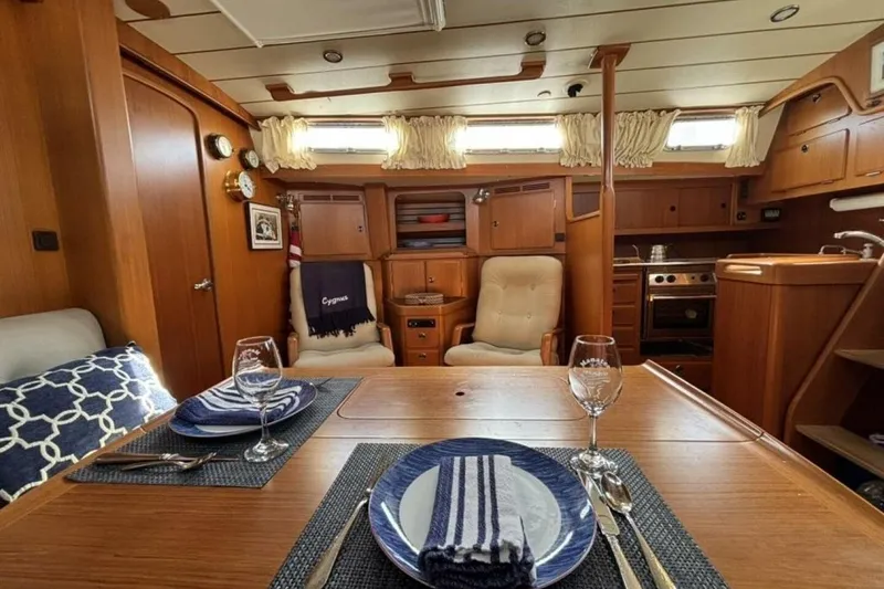 Slide: The Image of Interior of 2000 Hallberg-Rassy 46 yacht, featuring elegant dining area and cozy seating. - 7