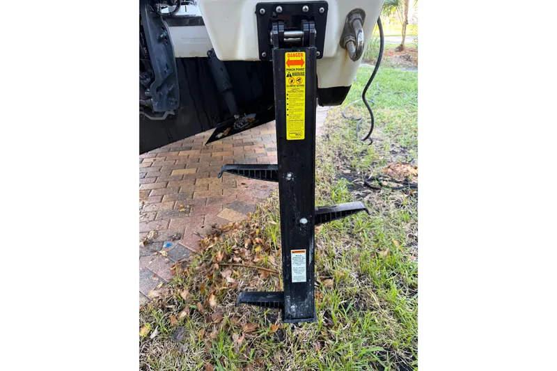 Slide: The Image of 2017 Pursuit DC 295 Dual Console boat trailer jack on grassy area. - 21