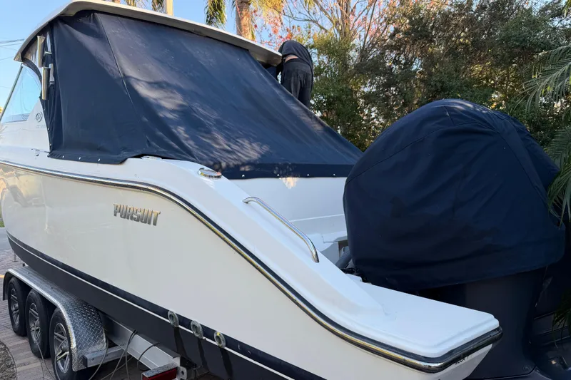 Slide: The Image of 2017 Pursuit DC 295 Dual Console boat on trailer, covered and parked outdoors. - 22