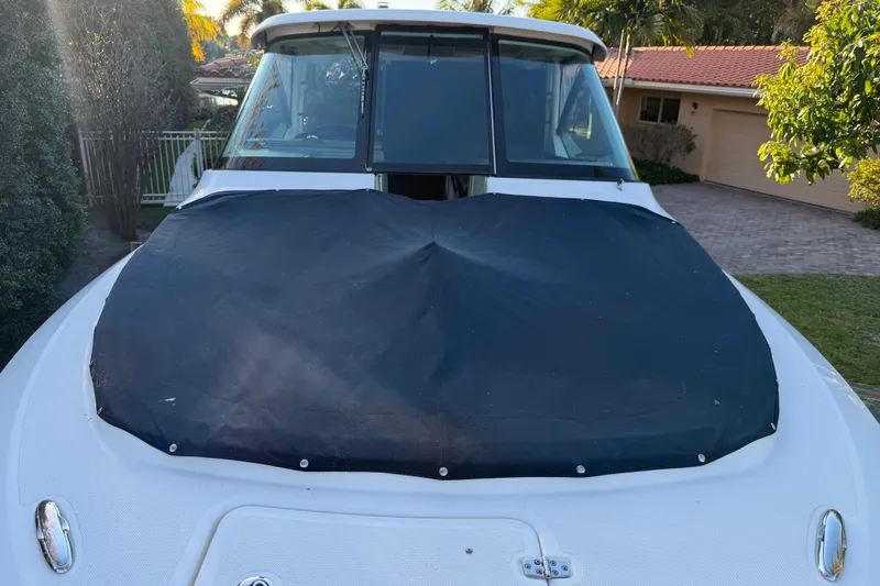 Slide: The Image of 2017 Pursuit DC 295 Dual Console boat with black cover, parked in a residential driveway. - 23