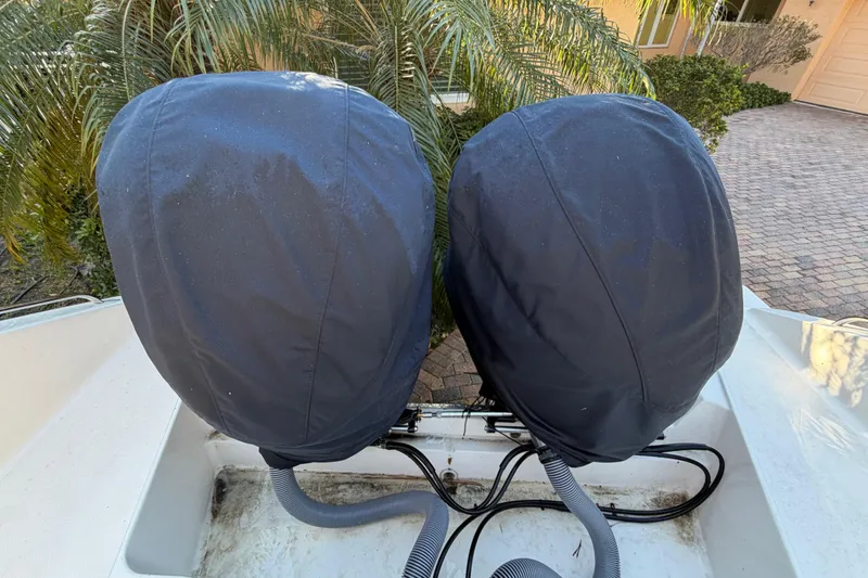 Slide: The Image of Covered engines on a 2017 Pursuit DC 295 Dual Console boat, parked near palm trees. - 29