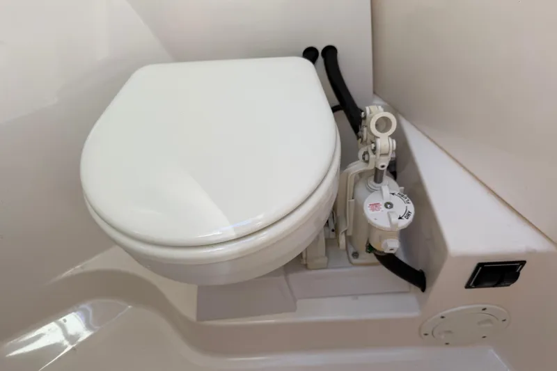Slide: The Image of 2017 Pursuit DC 295 Dual Console marine toilet with manual pump system. - 55