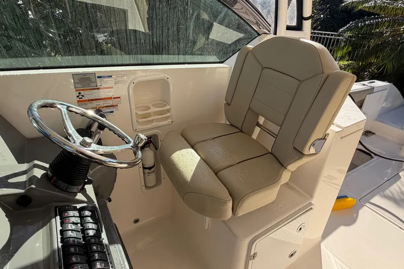 Slide: The Image of 2017 Pursuit DC 295 Dual Console boat helm with steering wheel and beige captain's chair. - 59