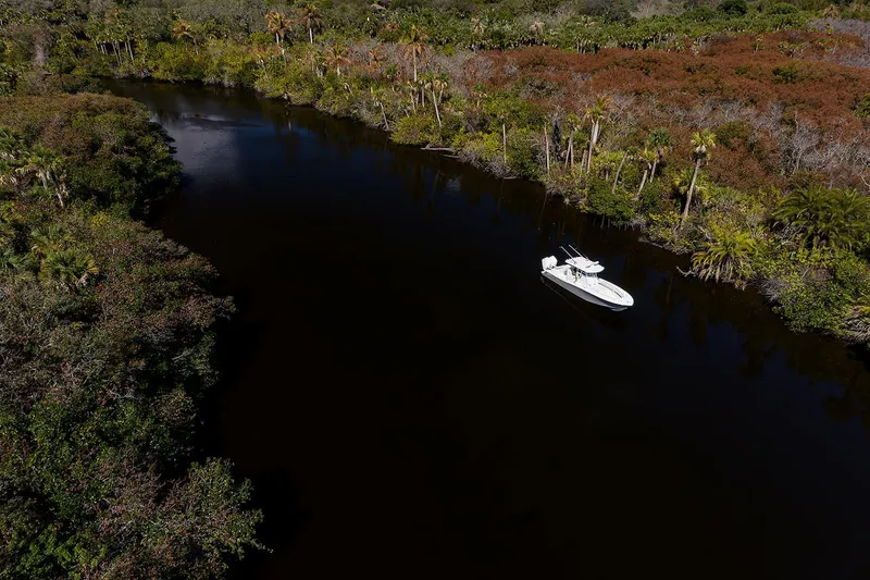 Slide: The Image of 2024 Invincible 33 Open Fisherman boat on a serene river surrounded by lush greenery. - 10