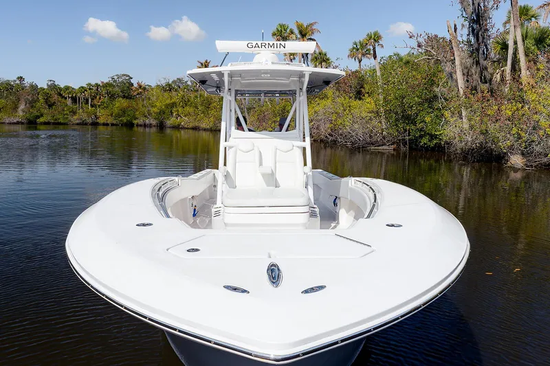 Slide: The Image of 2024 Invincible 33 Open Fisherman boat on calm water, surrounded by lush greenery. - 5