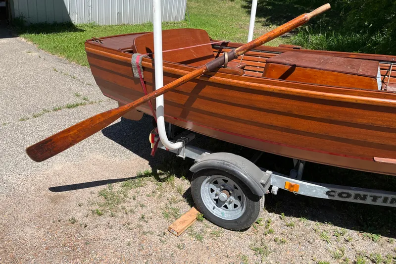 Slide: The Image of Vintage 1938 wooden yacht tender on trailer with oar, parked outdoors. - 13
