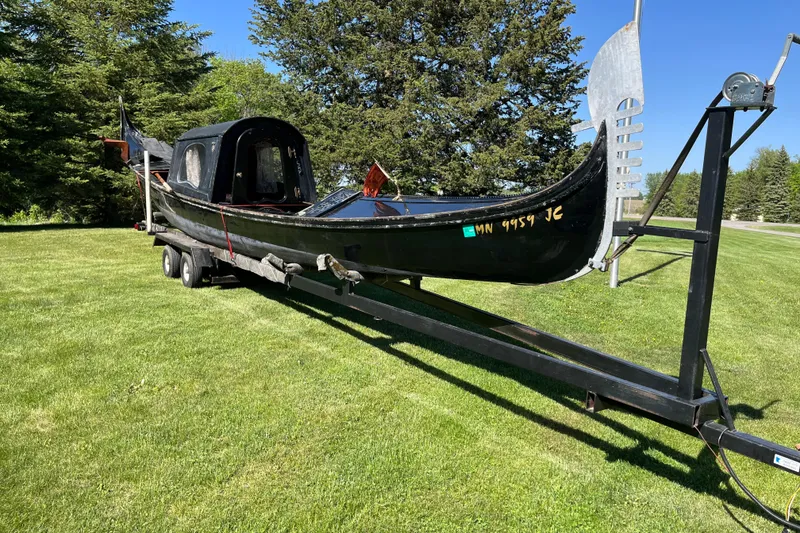 The Image of 1985 GONDOLA utility model on trailer, parked on grassy field with trees in background. - 1