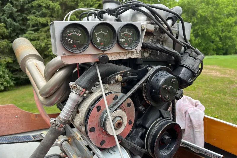 Slide: The Image of 1990 Thai Longboat utility engine with gauges, set against a green outdoor backdrop. - 8