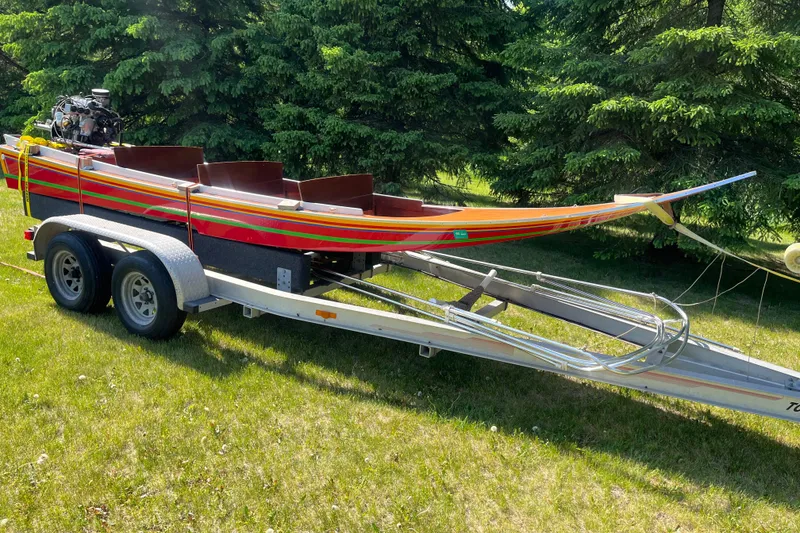 Slide: The Image of 1990 Utility Series Thai Longboat on trailer, vibrant colors, parked on grass. - 4