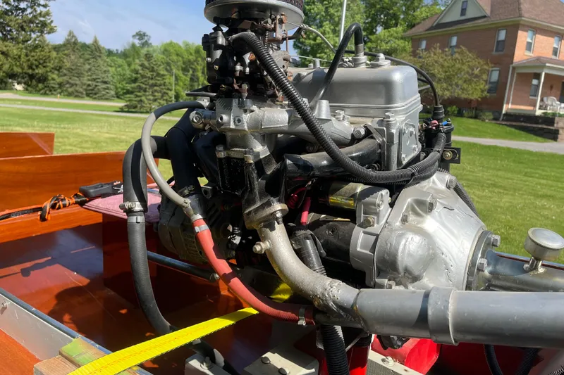 Slide: The Image of Engine of a 1990 Utility Series Thai Longboat, displayed outdoors with a house in the background. - 8