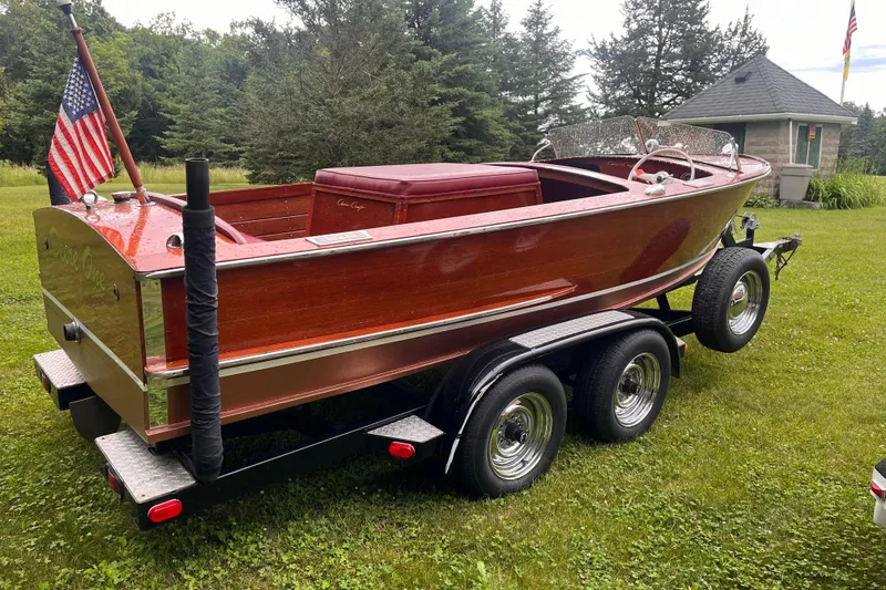 Slide: The Image of 1956 Chris-Craft 17 Sportsman boat on trailer, American flag, lush green background. - 3