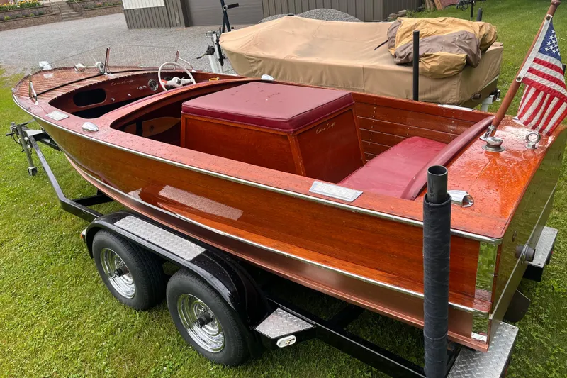 Slide: The Image of 1956 Chris-Craft 17 Sportsman wooden boat on trailer, featuring classic design and American flag. - 5