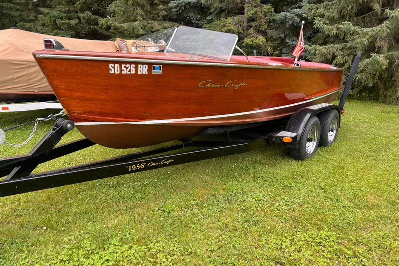 Slide: The Image of 1956 Chris-Craft 17 Sportsman boat on trailer, parked on grass with trees in background. - 8