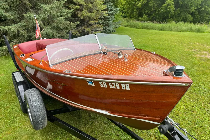 Slide: The Image of 1956 Chris-Craft 17 Sportsman wooden boat on trailer, surrounded by lush greenery. - 9
