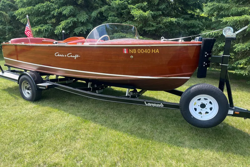 The Image of 1955 Chris-Craft 17 Sportsman boat on trailer, displayed on grass with trees in background. - 1