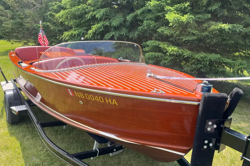 Slide: The Image of 1955 Chris-Craft 17 Sportsman boat on trailer, surrounded by lush greenery. - 3