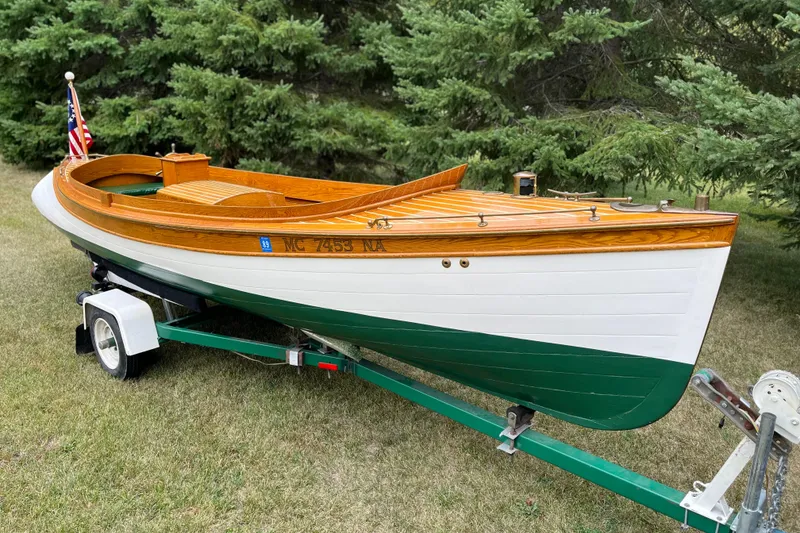 The Image of Vintage 1908 Outing launch boat on trailer, wooden deck, American flag, green and white hull. - 1