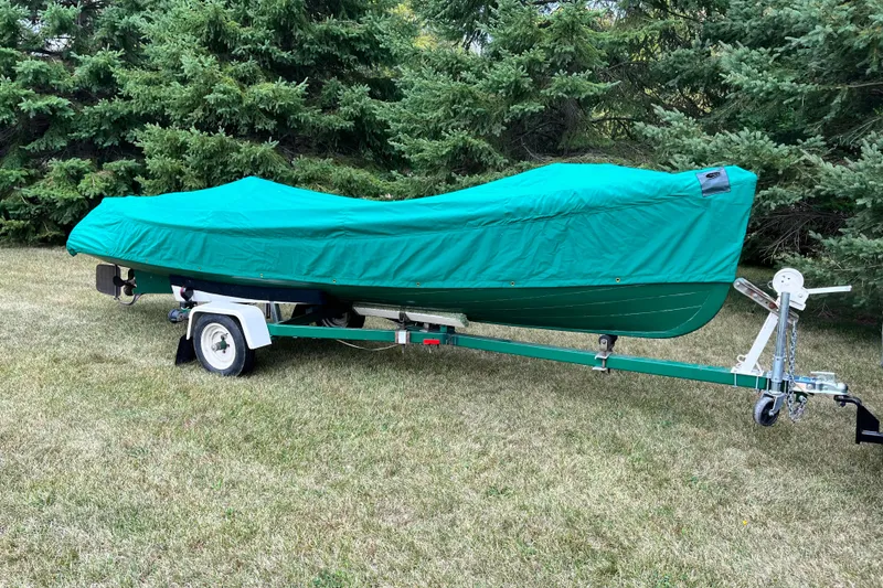 Slide: The Image of Covered 1908 Outing launch boat on trailer, parked on grass with trees in background. - 18