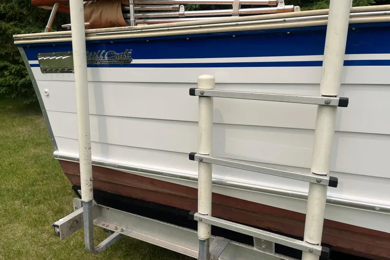 Slide: The Image of 1979 Skiff Craft 24 Flybridge boat with ladder, docked on grassy area. - 10