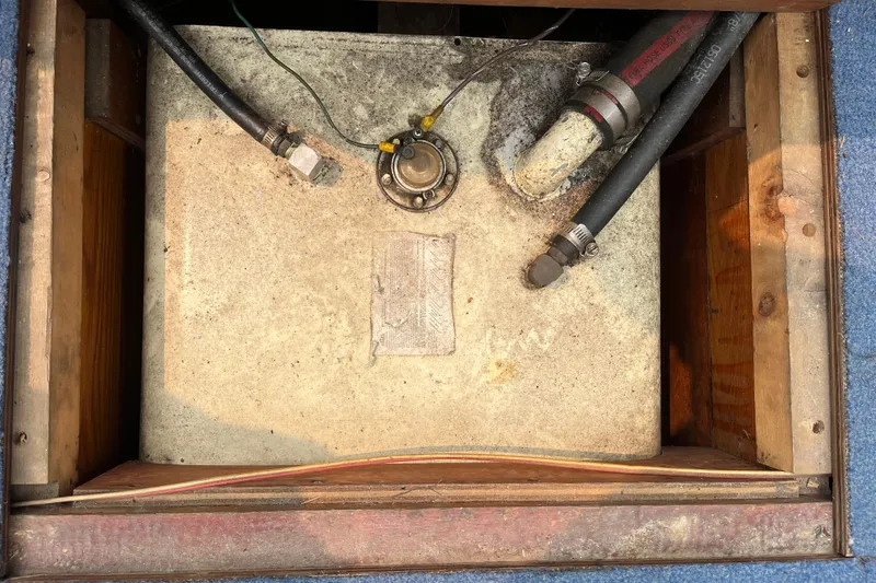 Slide: The Image of 1979 Skiff Craft 24 Flybridge fuel tank with hoses and fittings in wooden compartment. - 19