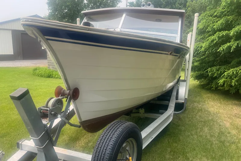 Slide: The Image of 1979 Skiff Craft 24 Flybridge boat on trailer, parked on grass near trees. - 4