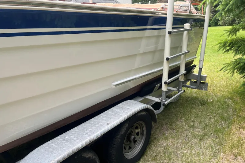 Slide: The Image of 1979 Skiff Craft 24 Flybridge boat on trailer, side view with ladder, parked on grass. - 6