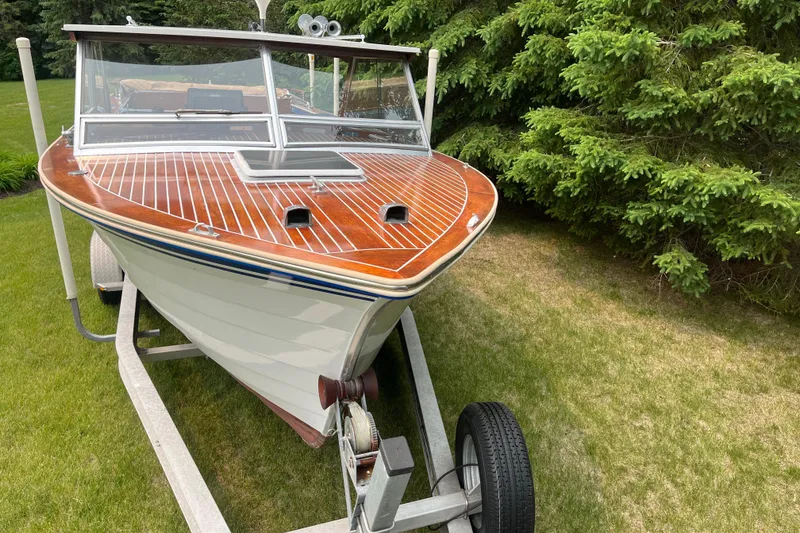 Slide: The Image of 1979 Skiff Craft 24 Flybridge boat on trailer, wooden deck, surrounded by greenery. - 8