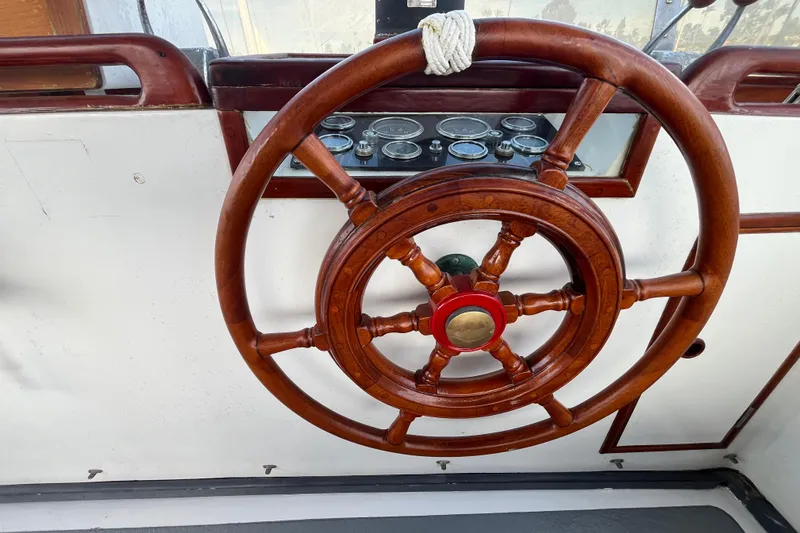 Slide: The Image of Wooden steering wheel of a 1978 Marine Trader 40 boat, with visible gauges. - 14