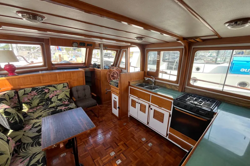 Slide: The Image of 1978 Marine Trader 40 interior with wood accents, floral sofa, and kitchen area. - 16
