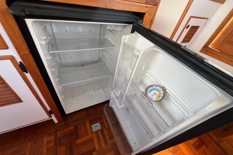 Slide: The Image of Open refrigerator inside a 1978 Marine Trader 40 boat, showing empty shelves and a thermometer. - 24