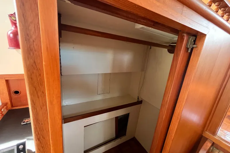 Slide: The Image of 1978 Marine Trader 40 interior wooden cabinet with open door, showcasing storage space. - 34