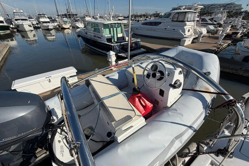 Slide: The Image of Inflatable boat with steering console docked at marina, surrounded by various yachts. - 90