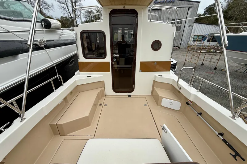Slide: The Image of 2017 Ranger Tugs R-25 boat deck with seating and railing in a marina setting. - 15