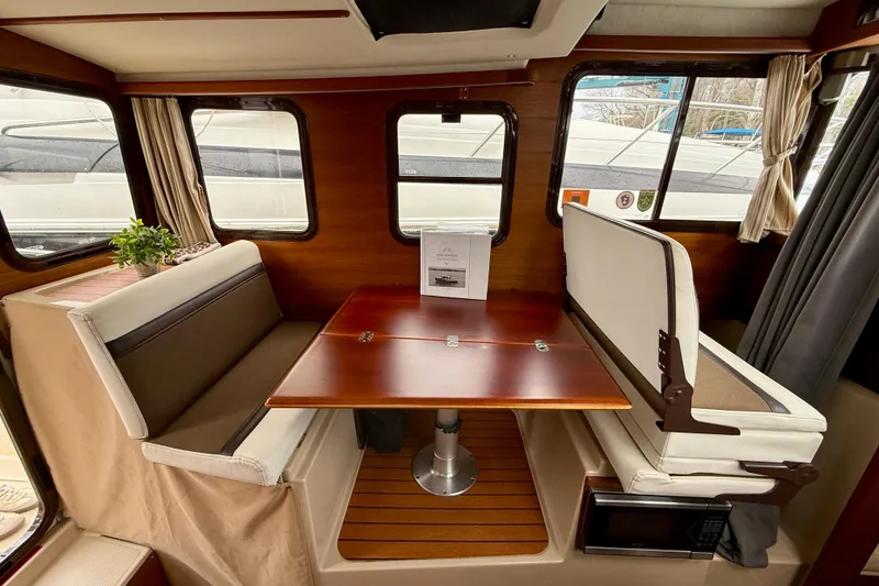 Slide: The Image of 2017 Ranger Tugs R-25 interior with dining area, wooden table, and cushioned seating. - 5