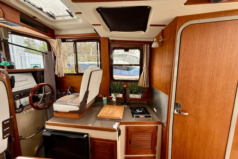 Slide: The Image of 2017 Ranger Tugs R-25 interior with helm, kitchenette, and wooden cabinetry. - 6
