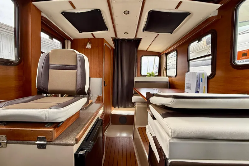 Slide: The Image of Interior of a 2017 Ranger Tugs R-25 boat, featuring seating and wood paneling. - 7