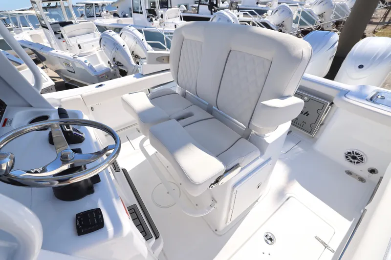 Slide: The Image of 2026 Sea Hunt Gamefish 25 boat interior with steering wheel and cushioned seating. - 17
